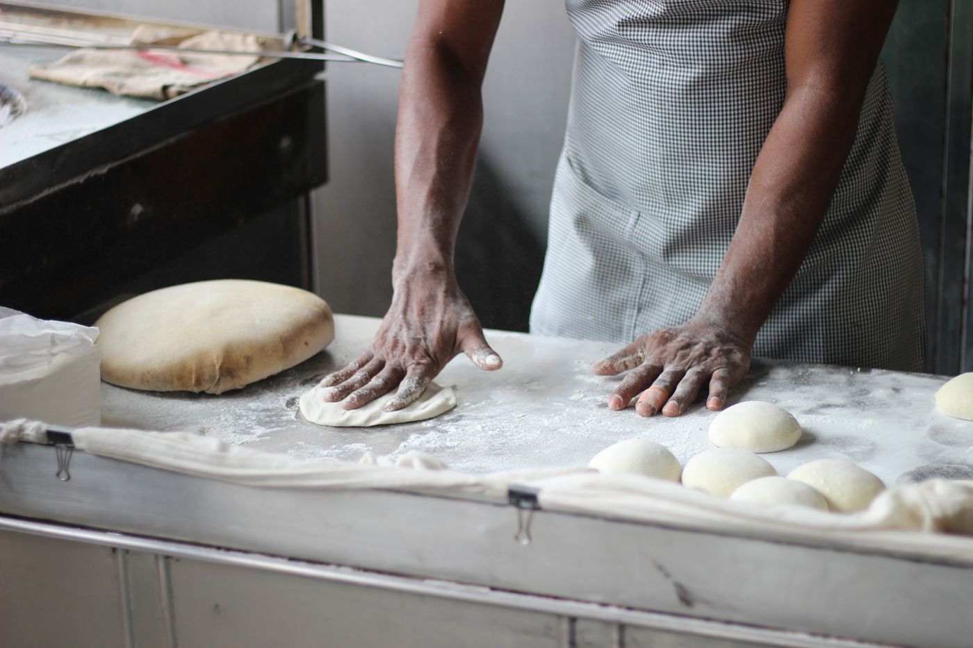 A baker working dough on a counter