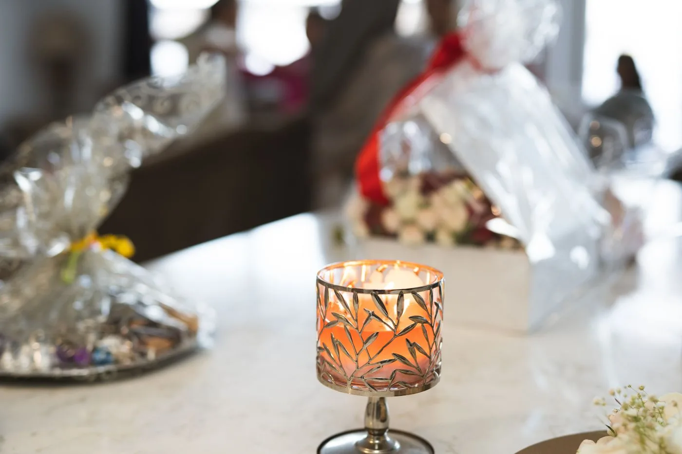Lit candle and wrapped gifts on a table