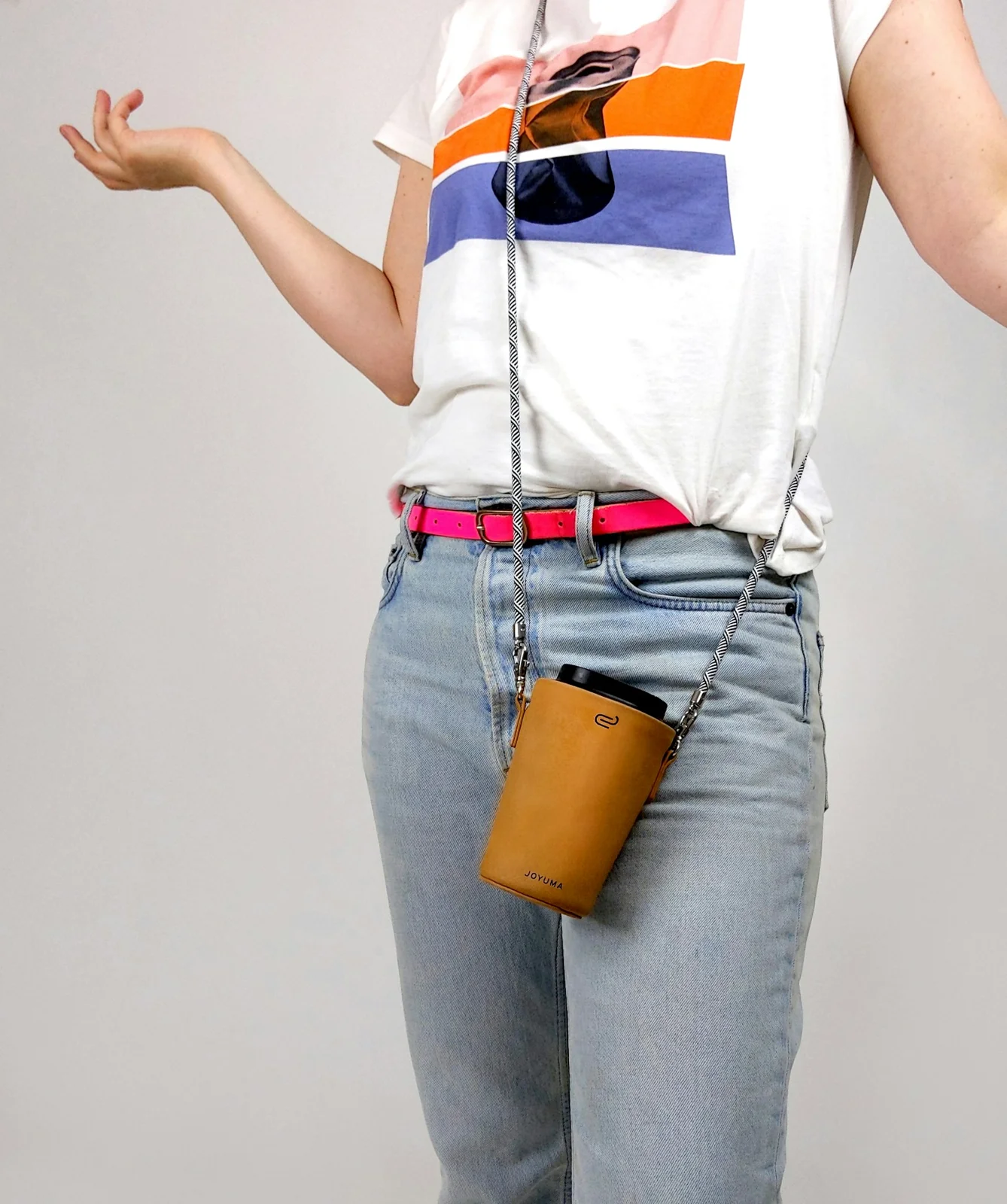 A person in a white shirt and jeans holding a takeaway coffee cup.
