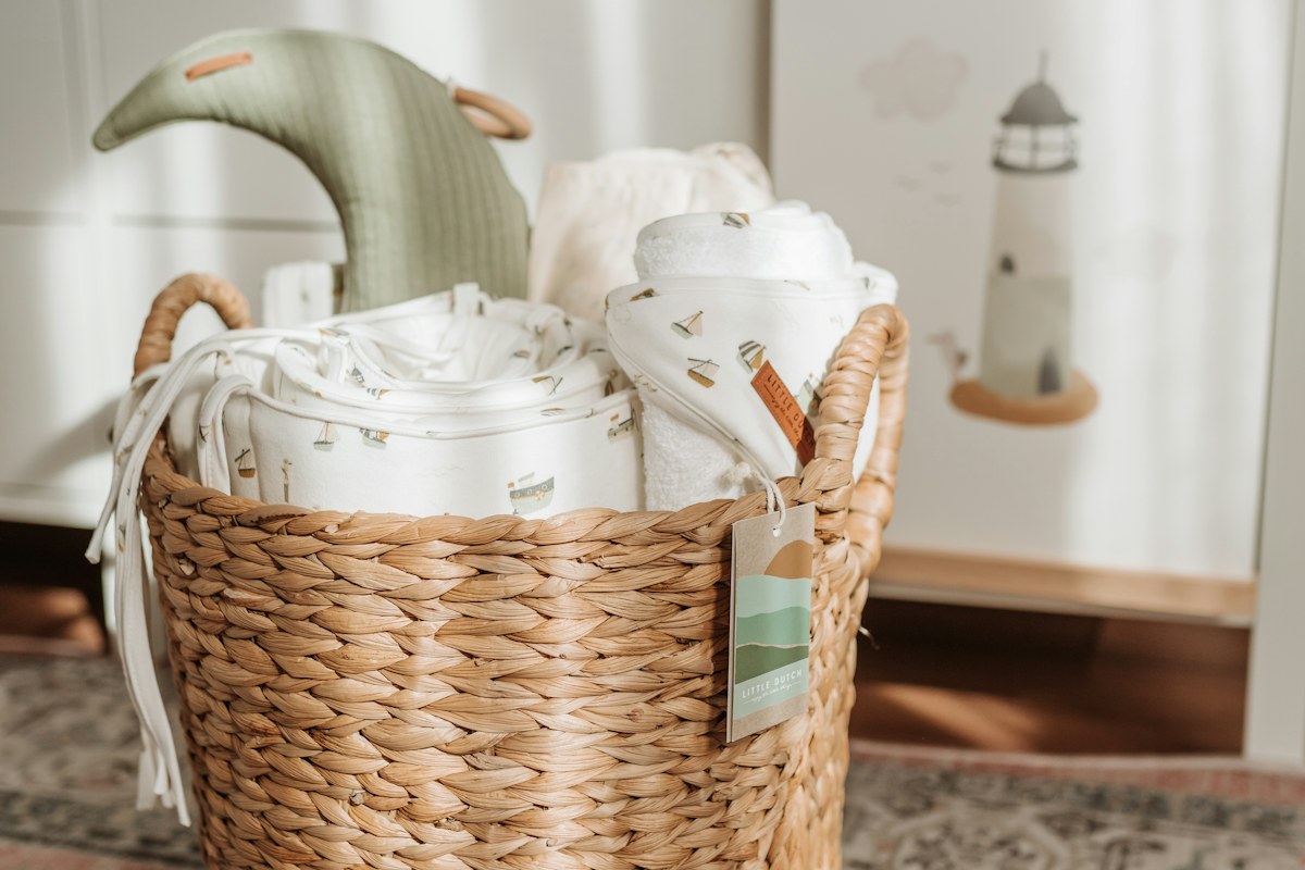 A woven basket holding ceramic teaware beside a pale green pitcher.