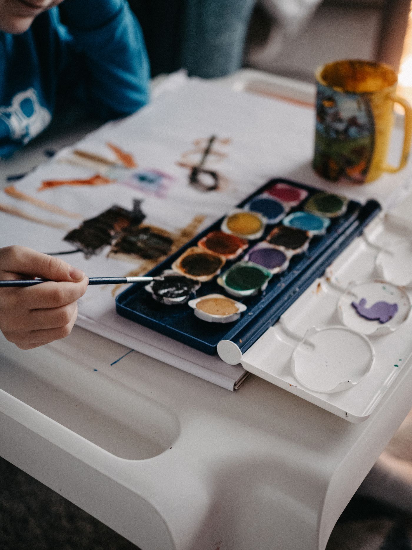 A child painting with watercolors at a table indoors