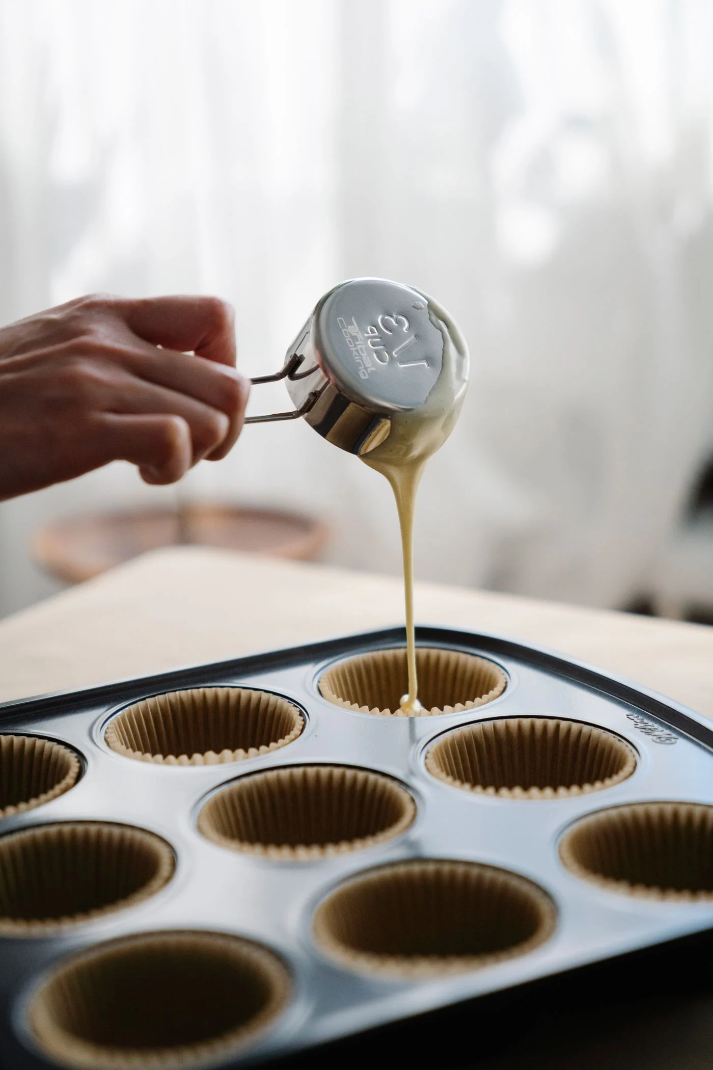 A person pouring batter into muffin liners
