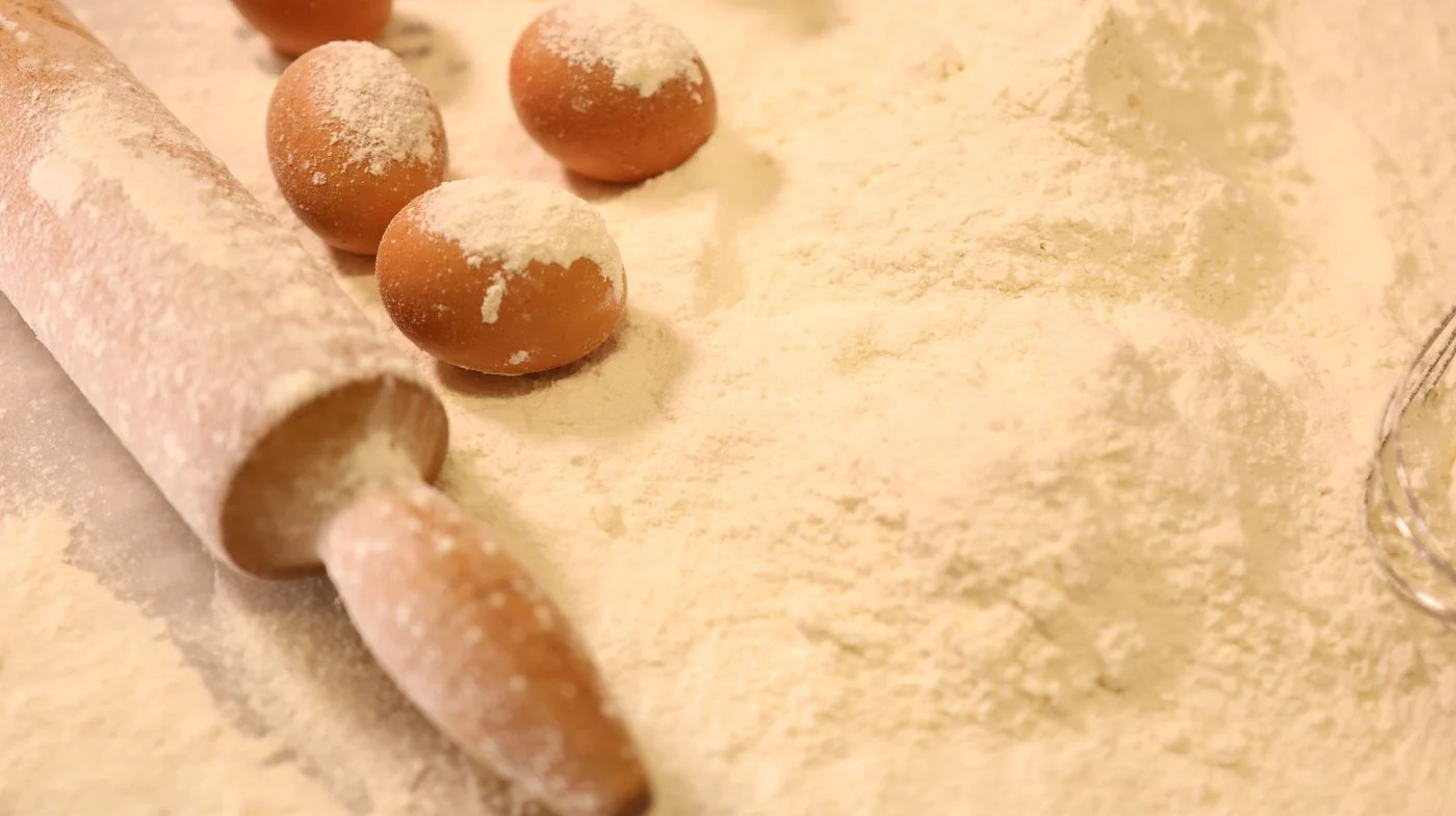 Eggs, flour and a rolling pin arranged for baking