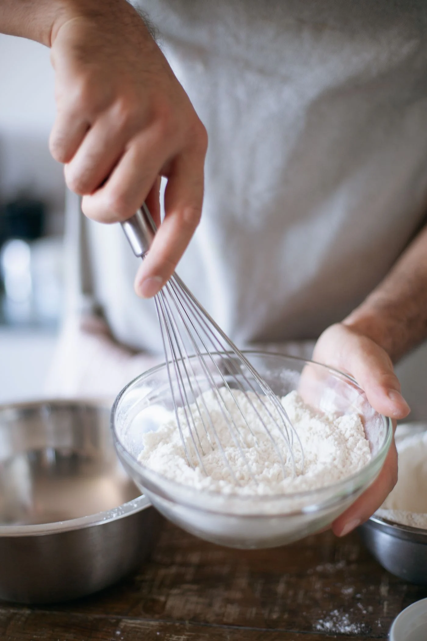 A person whisking ingredients in a glass mixing bowl