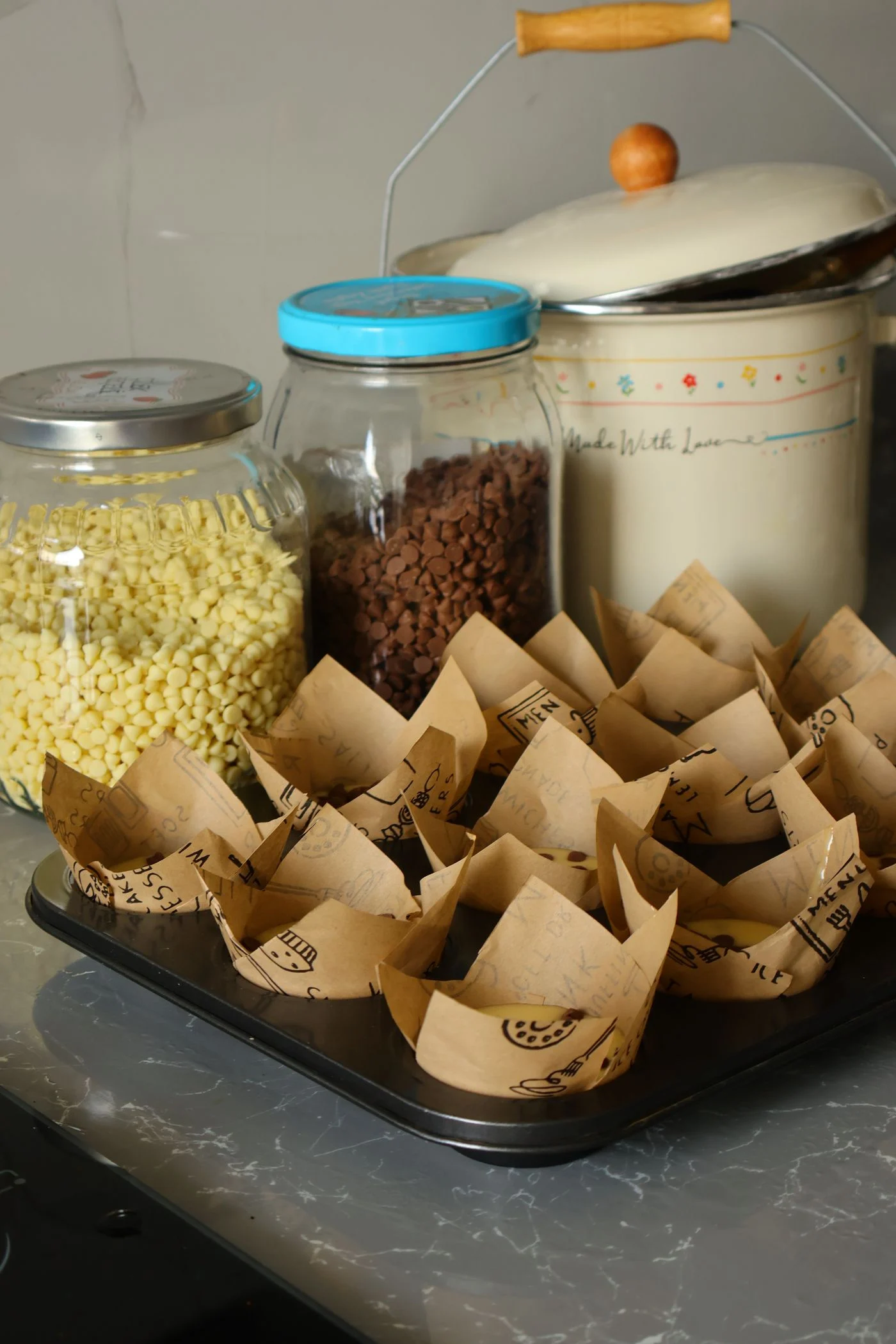 Ingredient jars and empty muffin liners arranged for baking