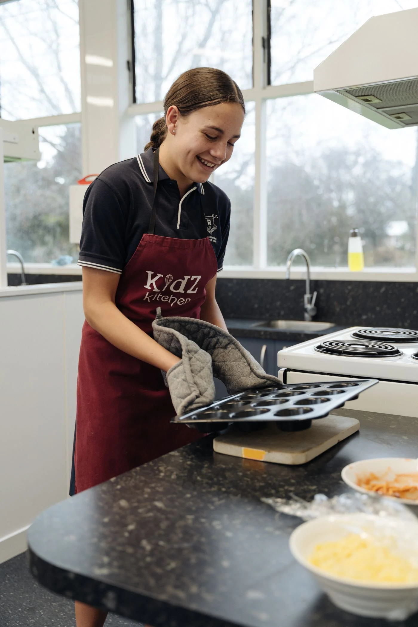 A woman holding a baking tray in a kitchen