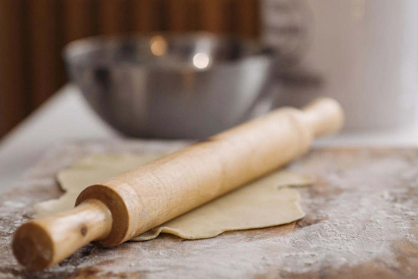 A wooden rolling pin resting over dough on a work surface
