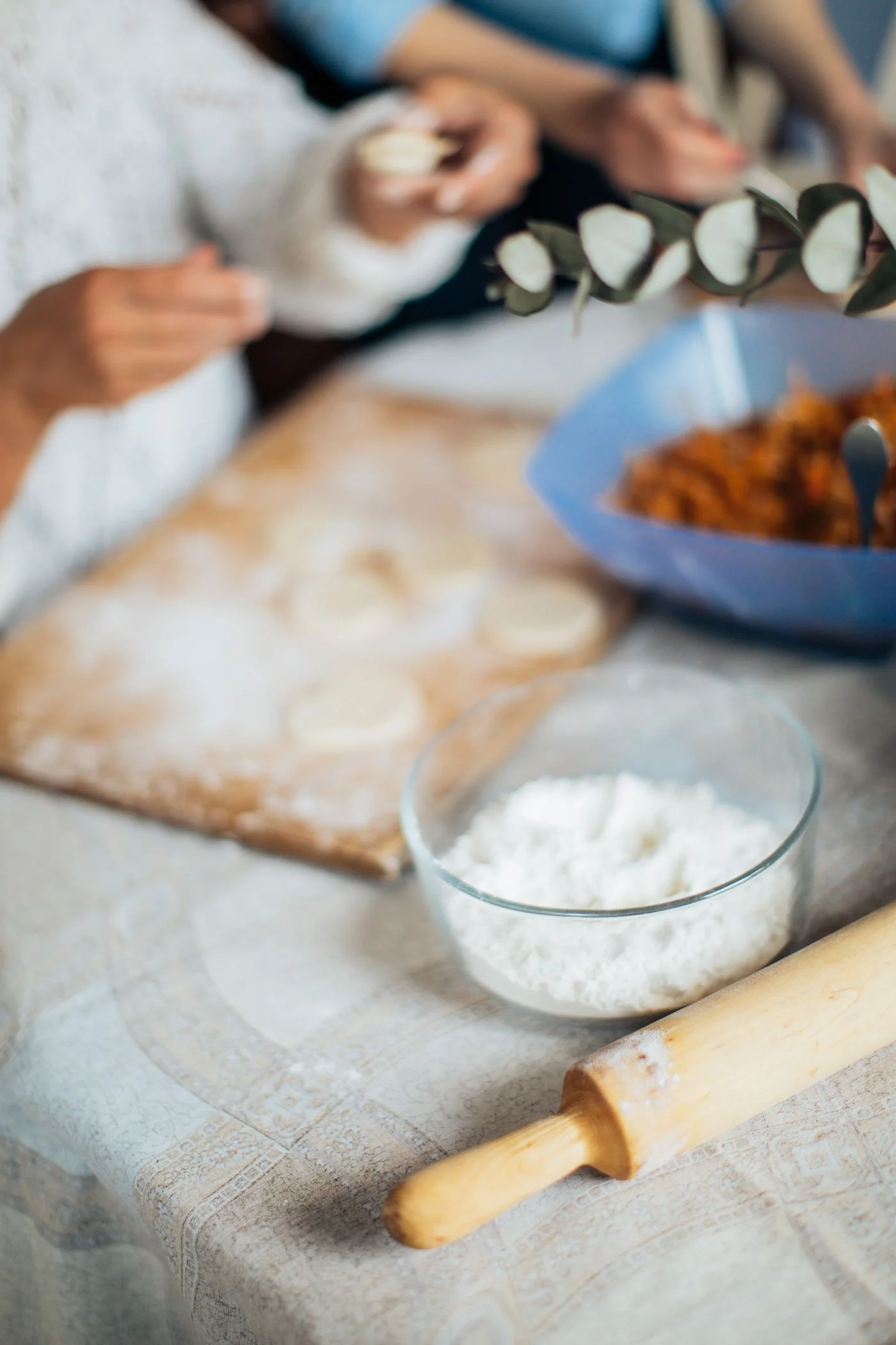 Hands preparing dough beside flour and a rolling pin
