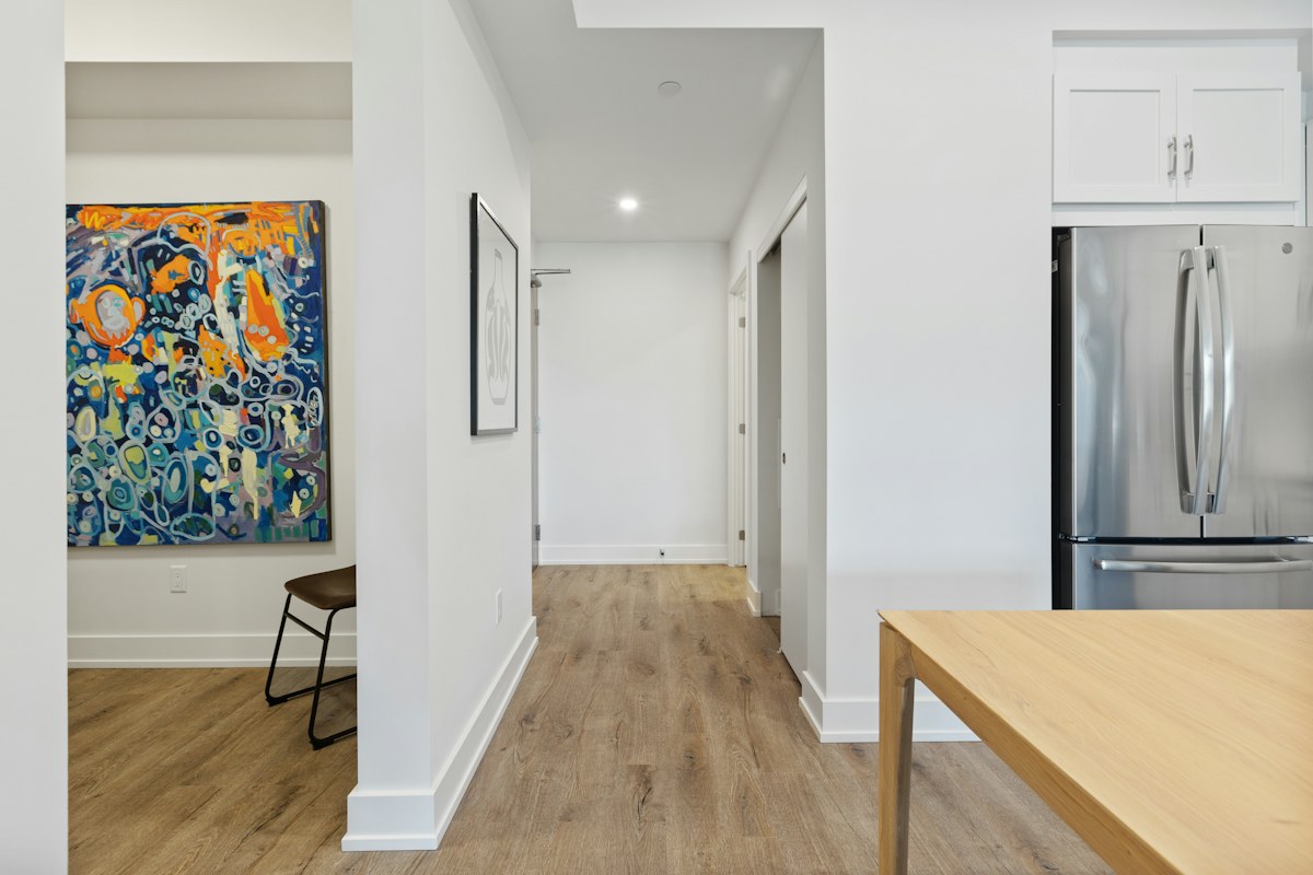 A light kitchen with wooden island, refrigerator and wall artwork