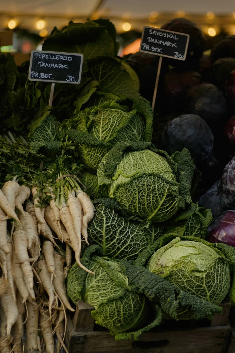 Fresh cabbages and other vegetables piled at a market stall